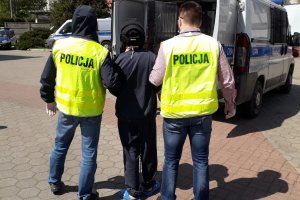 Zdjęcie przedstawia zatrzymanego prowadzonego przez policjantów