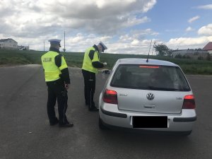 Zdjęcie przedstawia policjantów ruchu drogowego kontrolujących auto osobowe