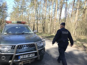 Zdjęcie przedstawia policjanta patrolującego las