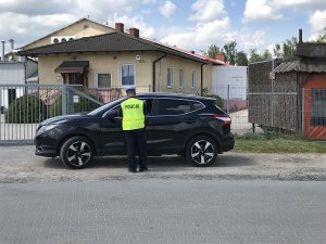 Zdjęcie przedstawia policjanta ruchu drogowego kontrolującego auto