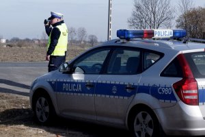 zdjęcie przedstawia policjanta ruchu drogowego kontrolującego prędkość aut