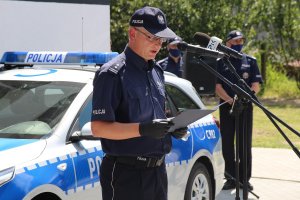 Zdjęcie przedstawia przemawiającego policjanta