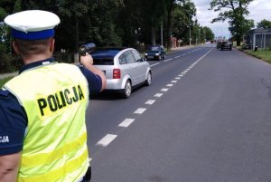 zdjęcie przedstawia policjanta ruchu drogowego mierzącego prędkość pojazdów