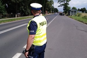 zdjęcie przedstawia policjanta ruchu drogowego mierzącego prędkość pojazdów