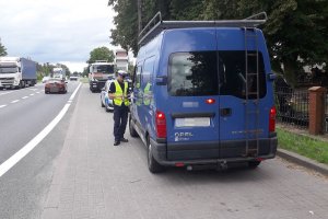 zdjęcie przedstawia policjanta ruchu drogowego kontrolującego pojazd typu bus