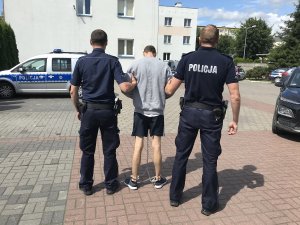 zdjęcie przedstawia zatrzymanego prowadzonego przez policjantów