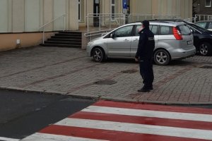 zdjęcie przedstawia umundurowanego policjanta kontrolującego przejście dla pieszych w rejonie szkoły