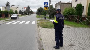 zdjęcie przedstawia umundurowanego policjanta kontrolującego przejście dla pieszych w rejonie szkoły