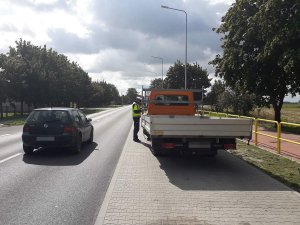 zdjęcie przedstawia policjanta ruchu drogowego kontrolującego auto dostawcze