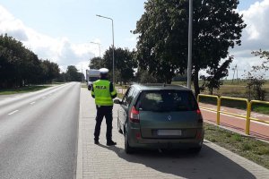 zdjęcie przedstawia policjanta ruchu drogowego kontrolującego pojazd