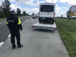 zdjęcie przedstawia policjanta ruchu drogowego sprawdzającego stan techniczny auta dostawczego