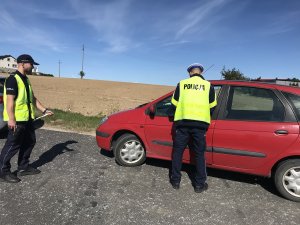 policjanci kontrolują auto koloru czerwonego