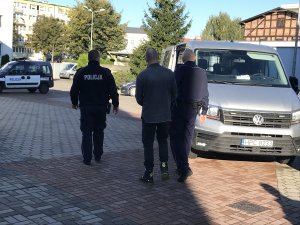 policjanci prowadzą osobę zatrzymaną