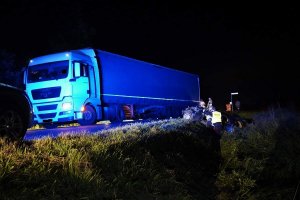 zestaw pojazdów stoi na drodze. w rowie auto osobowe, obok policjant