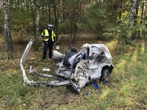 na pierwszym planie rozbite auto za nim policjant