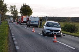 miejsce zdarzenia na pierwszym planie auto uczestniczące w kolizji w tle pojazdy służb ratowniczych