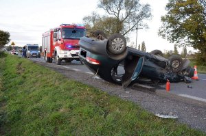 miejsce zdarzenia na pierwszym planie auto uczestniczące w kolizji w tle pojazdy służb ratowniczych