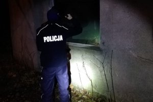 Policjant przez okno sprawdza opuszczony budynek