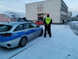 policjant kontroluje ruch aut przed szkołą