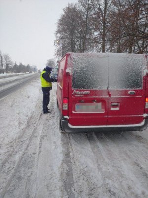 policjant sprawdza dokumenty kierowcy stojąc obok kontrolowanego busa