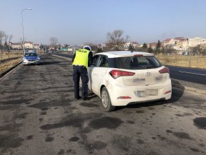 policjant kontroluje auto osobowe koloru białego