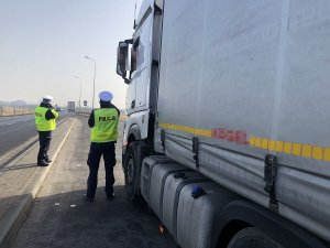 policjant kontroluje pojazd ciężarowy, w tle drugi policjant, który mierzy prędkość aut