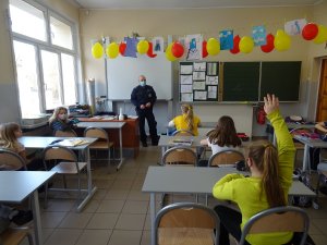 Dzielnicowy prowadzi zajęcia dla siedzących w klasie uczniów