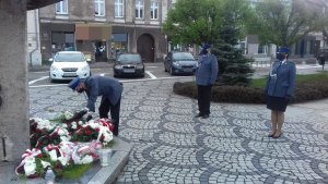 Delegacja przed pomnikiem. policjant składa kwiaty.