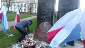 policjant składa znicz pod pomnikiem