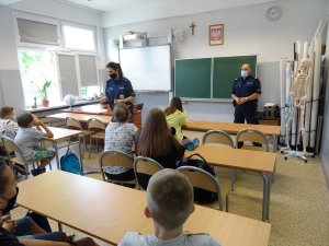 policjanci prowadzą pogadankę dla uczniów siedzący w klasie