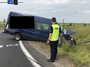 policjant stoi przy busie koloru niebieskiego