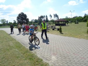 policjant obserwuje dziecko jadące na rowerze