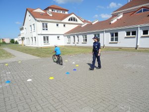 policjantka obserwuje dziecko jadące na rowerze