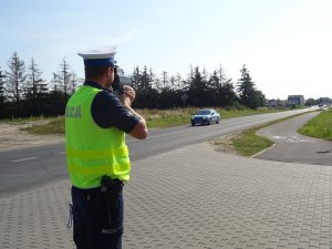 policjant drogówki mierzy prędkość aut urządzeniem