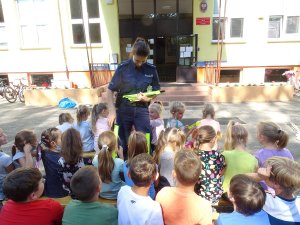 policjantka rozdaje uczniom odblaskowe opaski