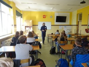 policjantka prowadzi zajęcia dla siedzących w ławkach uczniów