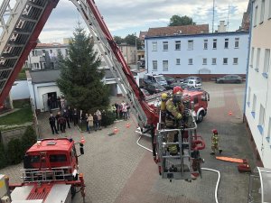 plac komendy, na nim ewakuowane osoby i pojazdy straży oraz policji