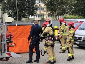 strażacy oraz policjant stoją na placu