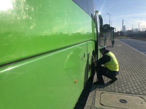 policjant sprawdza sprawność układu hamulcowego w autobusie