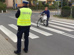 policjant obserwuje rowerzystkę przechodzącą przez pasy