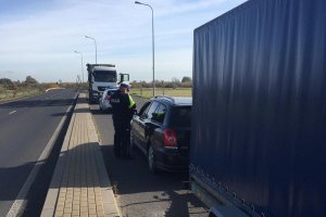 policjant kontroluje auto osobowe z przyczepą