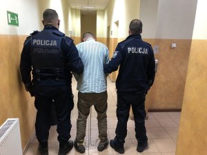 zatrzymany prowadzony przez umundurowanych policjantów