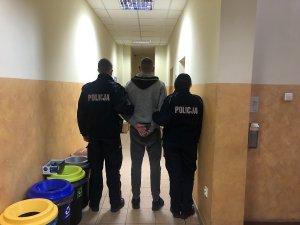 podejrzany prowadzony korytarzem przez policjantkę i policjanta