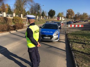 policjant zabezpiecza ruch pojazdów przy cmentarzu