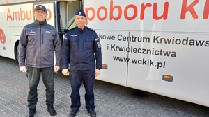 policjant wspólnie z przedstawicielem służby więziennej stoją przy autobusie