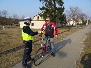 policjant wręcza odblaskową kamizelkę rowerzyście