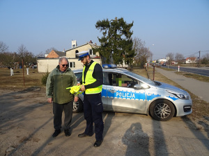 policjant przekazuje pieszemu kamizelkę