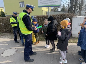 policjanci rozdają odblaskowe opaski