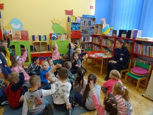 policjantka siedząc na krześle prowadzi zajęcia dla dzieci