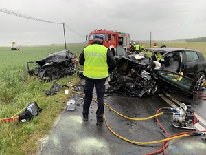 policjant ruchu drogowego na miejscu wypadku. w tle dwa rozbite auta